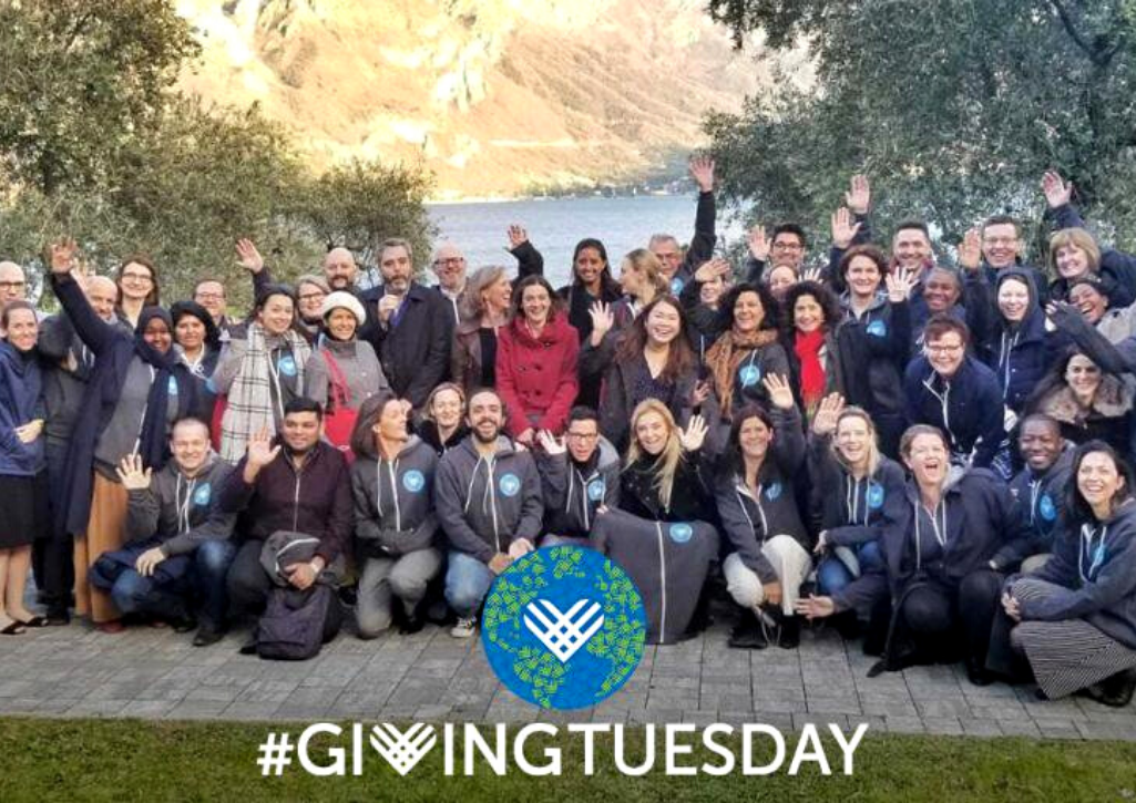 A group of 50 giving Tuesday workers smiling and waving at the camera