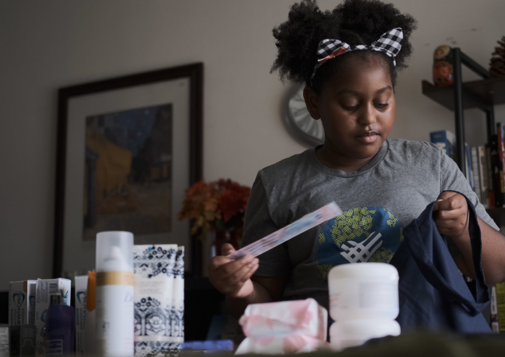 Khloe Thompson age 13 packing a tote bag full of toiletries