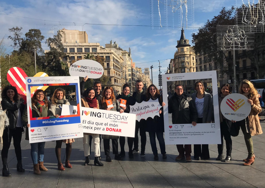 GivingTuesday Spain team celebrating on the street, holding Instagram selfie templates and posters