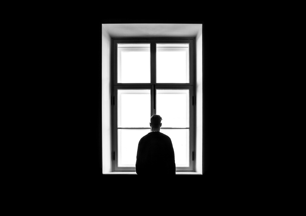 A silhouette of a man standing in a window