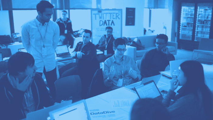 Multiple people sitting in a office working with a blue filter.