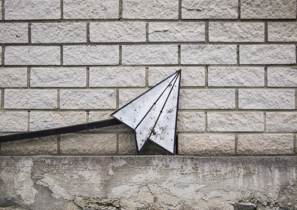 A paper airplane painting on a white brick wall