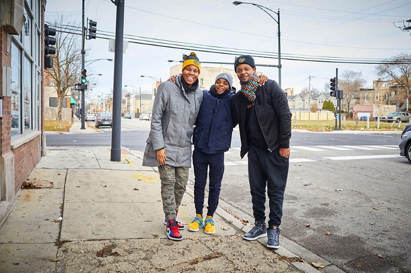 A family wearing GivingTuesday hats stands on a street corner in Chicago after handing out blessing bags to the homeless