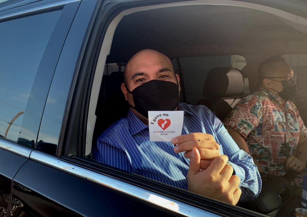 A man holding a GivingTuesday Guam sticker