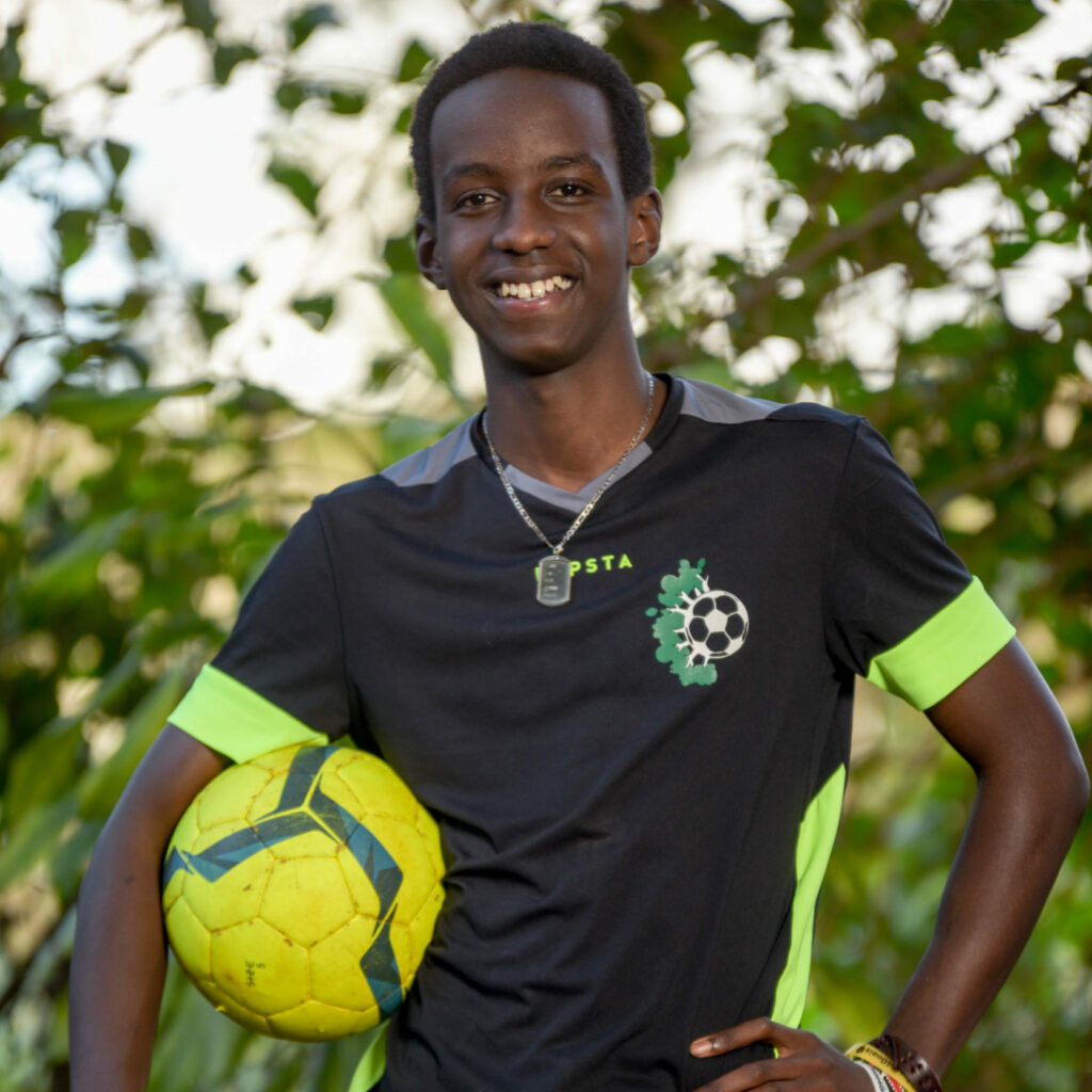 A person smiling and holding a yellow volleyball.