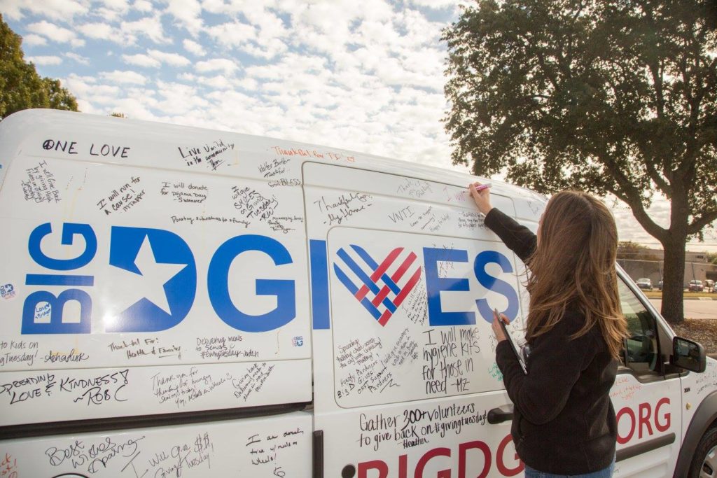 A person writing something on a BIG DGIVES Van