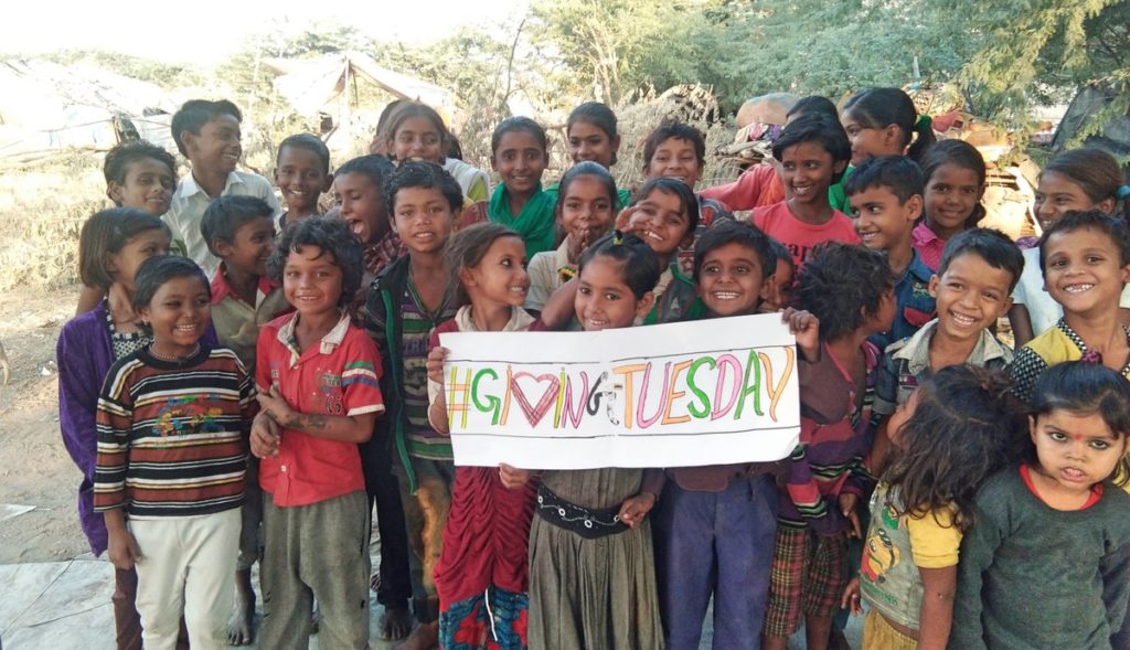 A group of kids holding a sign that says "#GivingTuesday"