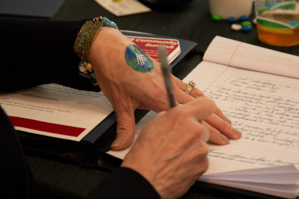 A person's hands writing in a notebook.