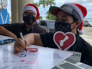 Two children draw on a poster in Guam.