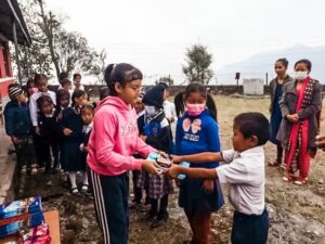 Young girl offering gifts to other children in Nepal