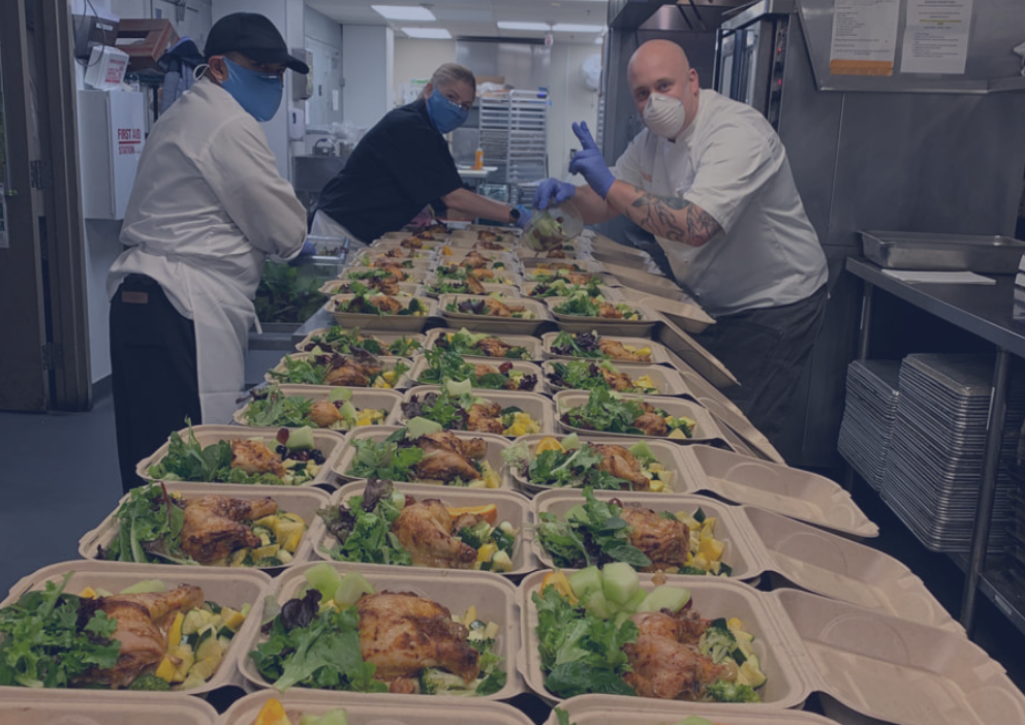 A group of volunteers preparing trays of food that they're going to give out for free to anyone who's hungry