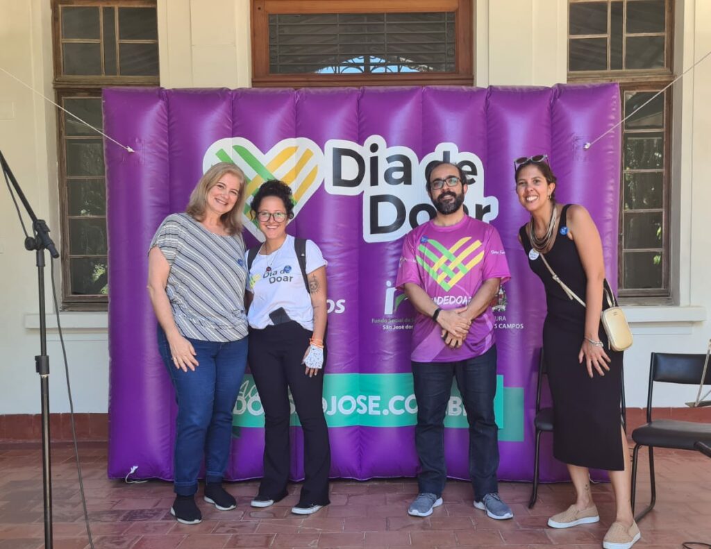 Brazil leaders standing next to a background that says Dia De Doar on it (with the GivingTuesday logo)