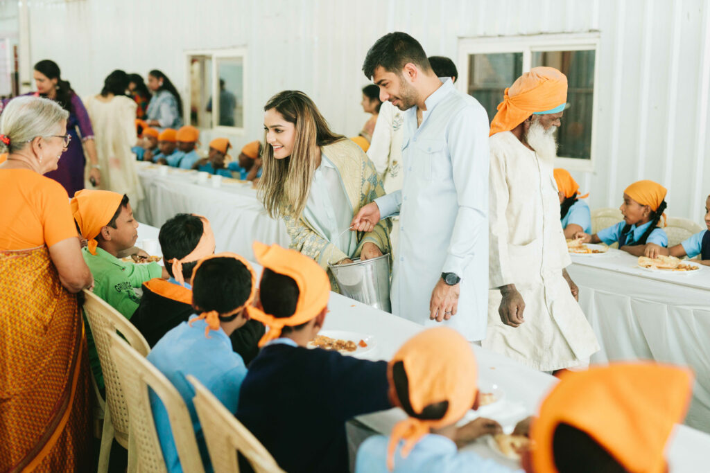 two people serving meals to others at their wedding