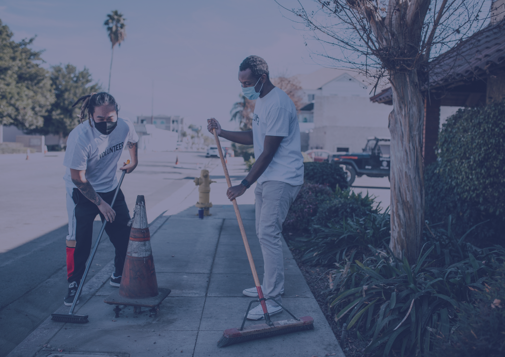 Two people sweeping up a street