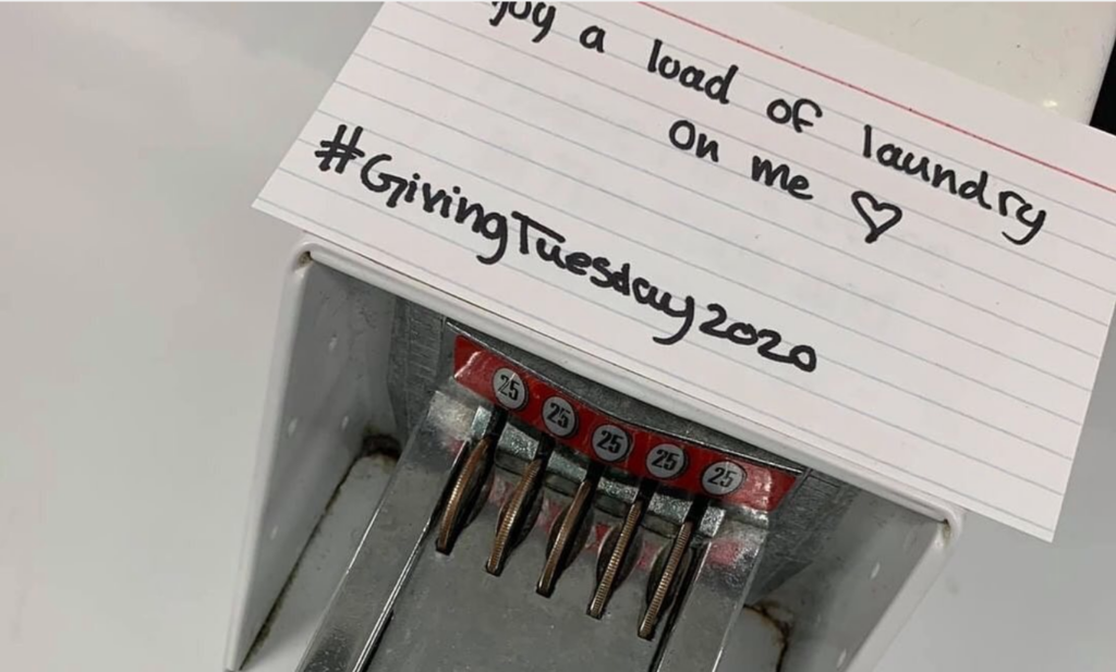 a washing machine with quarters in it. a note on top says "your load of laundry is on us - GivingTuesdayMiltary"