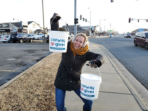 a woman holding two buckets that say Conway Gives on them